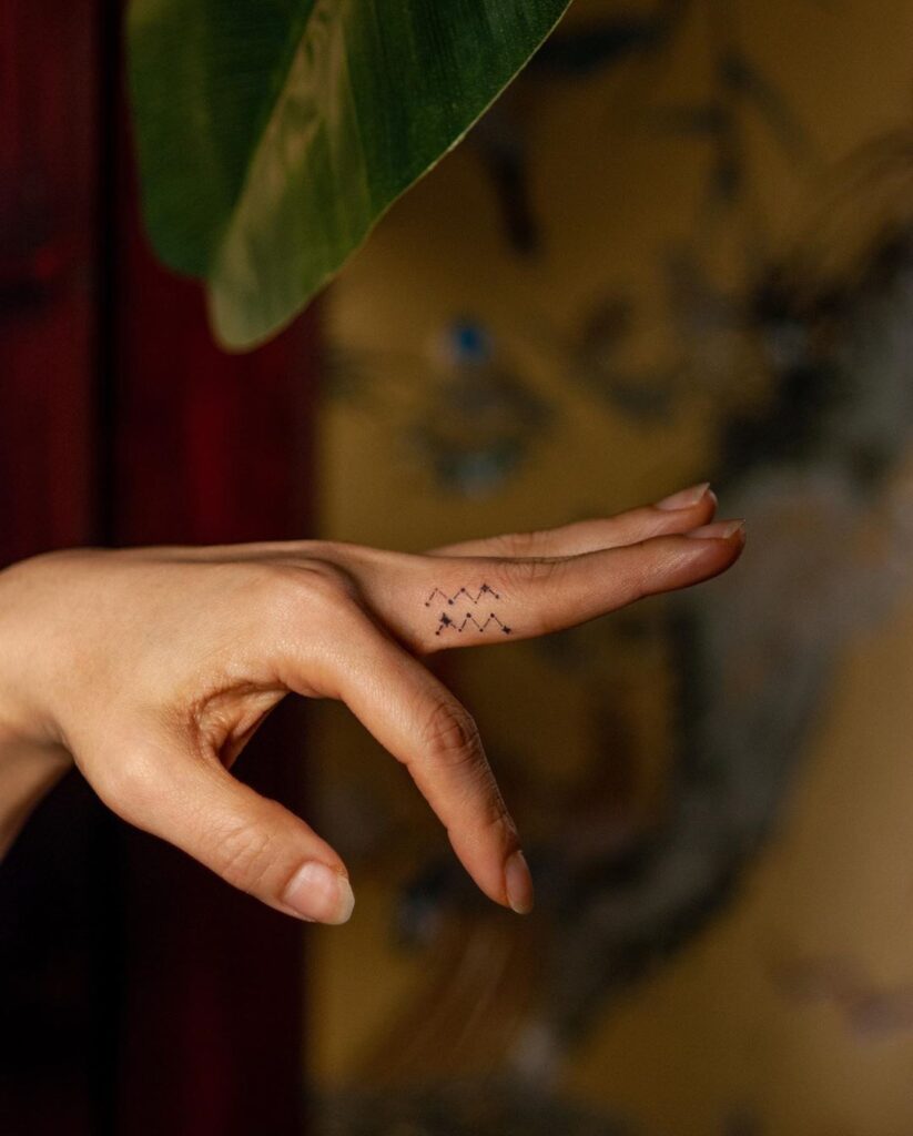 tatuagem do signo de aquario no dedo